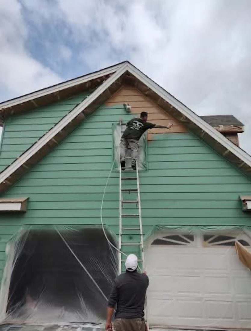 Crew spray-applying a new color on a home exterior