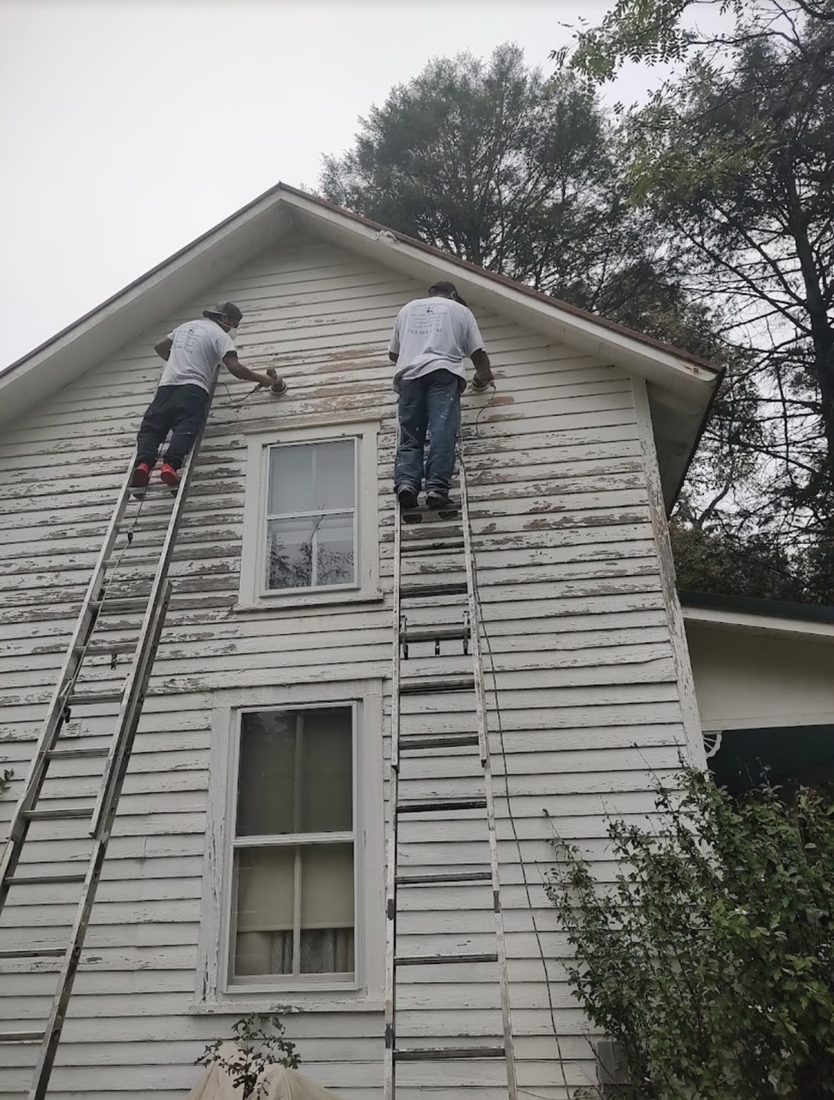 Hand-sanding peeling siding to prepare for repainting